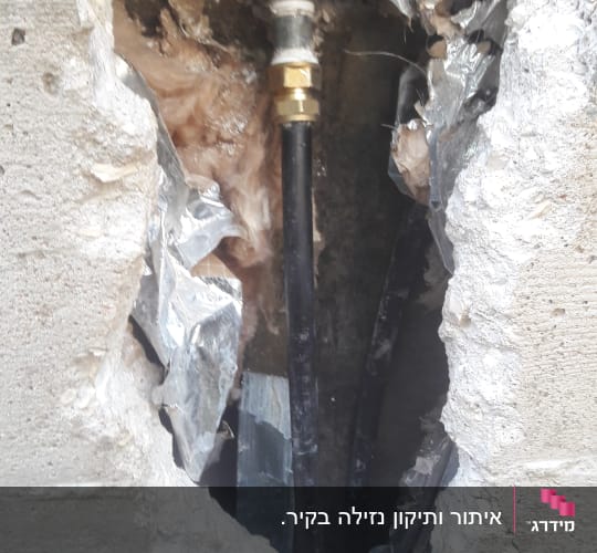צינור מים עם חיבורי מתכת בקיר שבור
